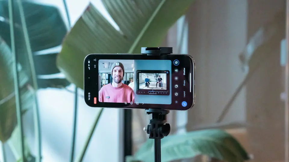 A smartphone on a tripod recording a creator, who appears on its screen